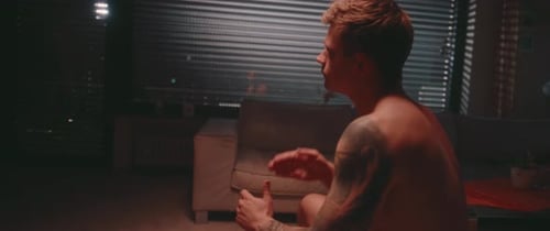 Shirtless Man Meditating in Apartment at Night