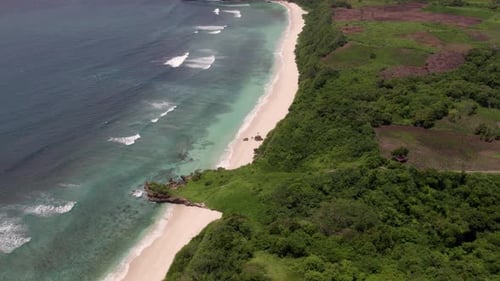 Aerial view of tropical beach with waves, rocks, cliff, Indonesia.