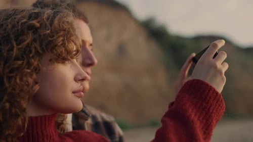 Affectionate lovers taking a sunset photo on smartphone at a beautiful sunrise beach
