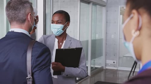 Mature African American Businesswoman Using Gun Thermometer to Check Body Temperature Of