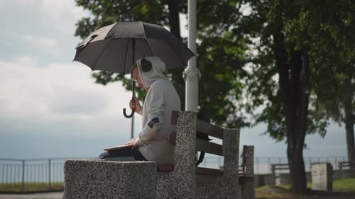 Man Under Umbrella Sitting on Bench in Park