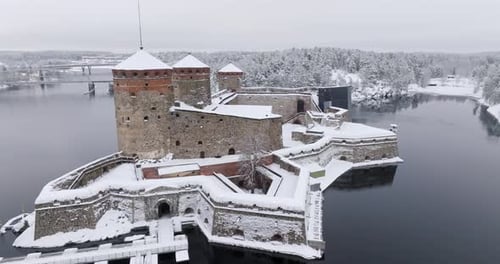 Drone orbiting the snowy Olavinlinna castle, winter day in Savonlinna, Finland