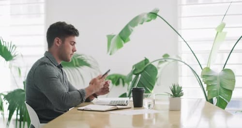 4k video footage of a young businessman using a cellphone while working in an office