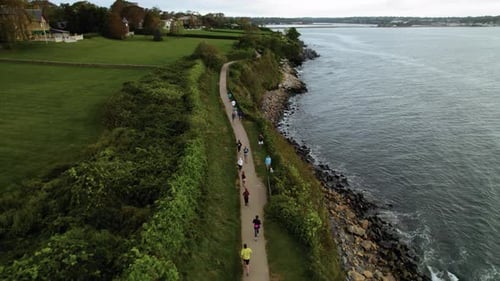 Luftbild von Läufern, die auf einem Pfad neben dem Meer laufen. Jogger trainieren in der Nähe einer felsigen Küste
am