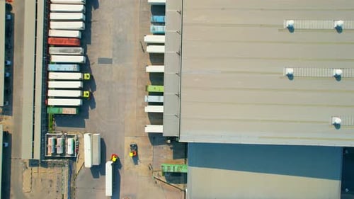Drohne fliegt über viele Frachtcontainer und Sattelschlepper