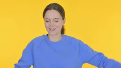 Woman Dancing Happily in Front of Yellow Background