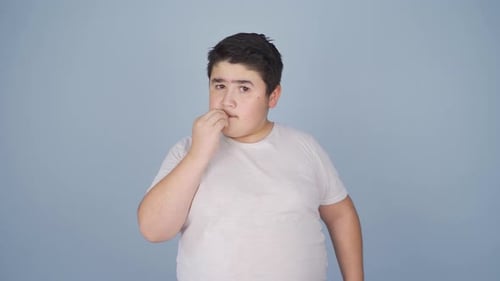 The boy is biting his nails.