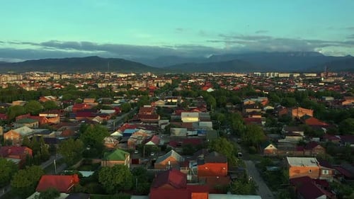 Stadt mit vielen Häusern und Bergen im Hintergrund in der Abenddämmerung mit blauem Himmel und Wolken