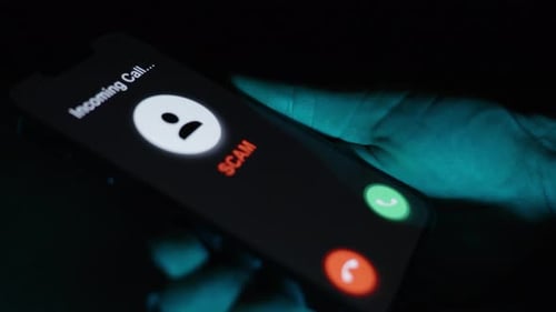 A closer view of the phone displaying a "SCAM" alert, emphasizing the choice to decline the