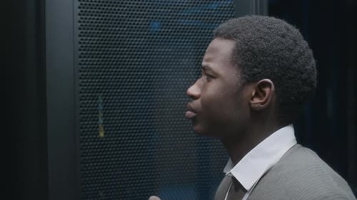 Schwarzer männlicher IT-Administrator analysiert die Arbeit des Mainframes im Rechenzentrum