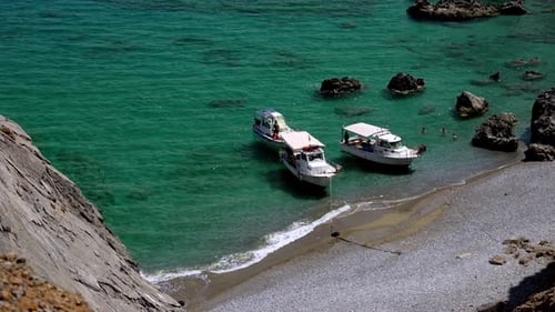 Three small boats with people moored at a deserted exotic beach , people swimming