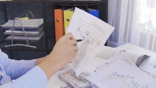 Man Reviews Data Graphs in Office Setting