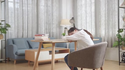 Back View Of Tired Asian Teenager Sleep On The Table At Home After Doing Home Work