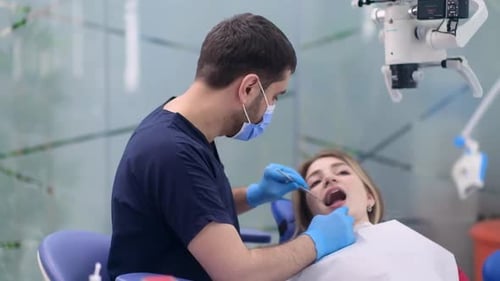 Dental Care in Modern Clinic Focused Orthodontist Looking at Teeth of Female Patient