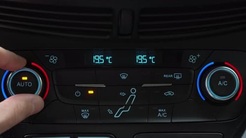 Fingers turn toggle switch of car air conditioner decreasing temperature in cabin low minimal