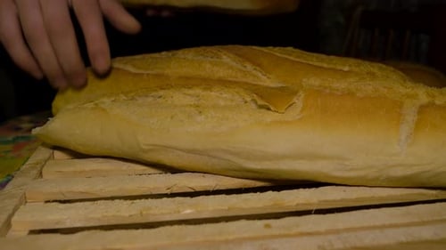 Der Mann entfernt einen Stapel galizischen Brotes und passt die Platzierung an, dann legt er frisches Brot über das Brett