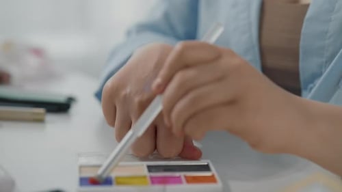 Closeup View of Young Lady Hands and Bright Eyeshadow Palette in Beauty Studio Professional Makeup