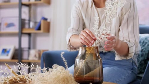 Woman arranging decorative dried flower arrangement in vase