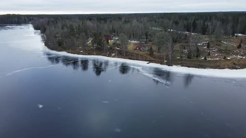 Aerial view of a few vacation homes at the edge of a frozen lake in rural Sweden