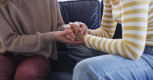 Two People Holding Hands Sitting on Couch
