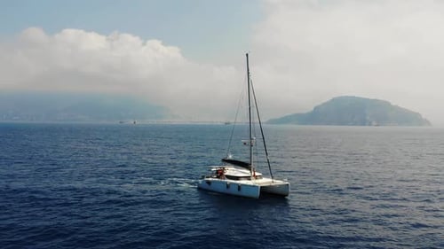 Sailing Catamaran Gracefully Gliding Across Tranquil Blue Waters with Gentle Waves and Distant