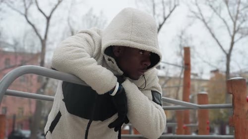 Young Man Resting on Iron Bar Breathing Heavily During Intense Winter Workout