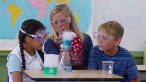 Teacher guides elementary school students through science experiment in classroom