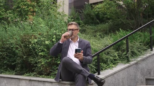 Happy Man Holding Smartphone and Drinking Coffee in the City Slow Motion