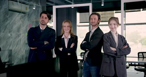 Multiracial group of adult entrepreneurs standing confidently in office with arms crossed