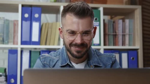 Retrato de un ambicioso joven hipster empleado de negocios que trabaja junto al monitor de una computadora portátil que parece temblar