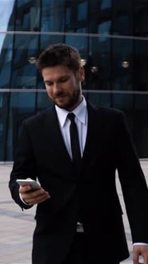 Vertical of Handsome Entrepreneur Reading Sms or Messenger Using App on Iphone in Business Centre