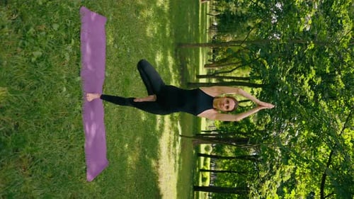 vertical video an experienced female instructor meditates park practices yoga does stretching