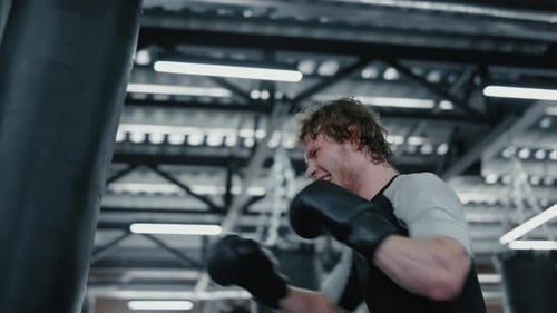 Aggressive kickboxer working on blows at gym training kicks in fitness center