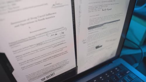 Divers fichiers confidentiels top secrets classifiés apparaissent sur l'écran d'un ordinateur portable dans une pièce sombre du bureau ou