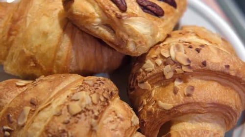 Close-Up of Golden Croissants Topped with Almonds and Pecans