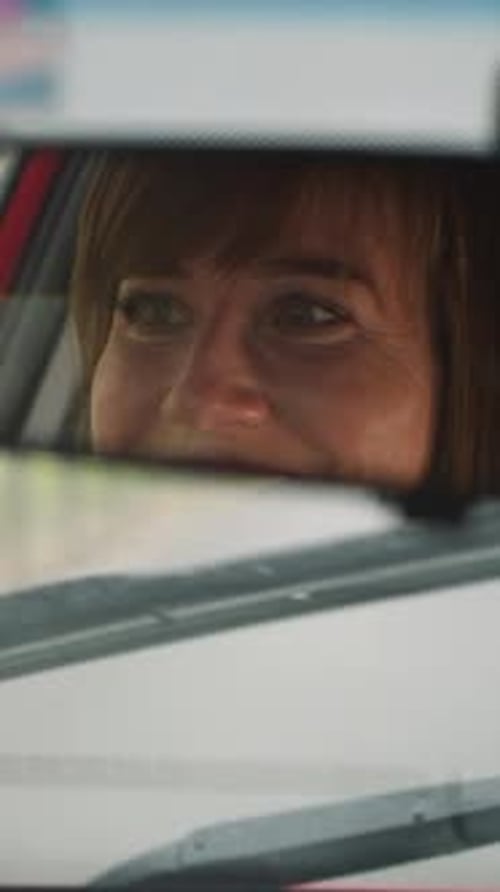 Cheerful Woman Smiles Driving Car on Empty Road on Rainy Day