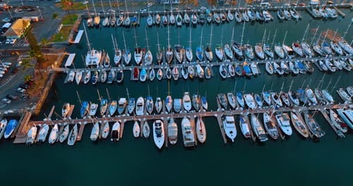 Multiple boats at the berth in the light of sunset. Footage over the yacht club of Honolulu