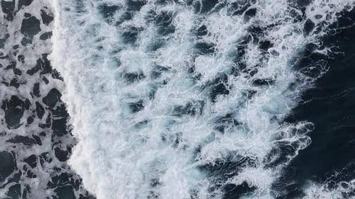An Aerial View of Ocean Waves Powerfully Crashing Onto the Shoreline is Truly Stunning