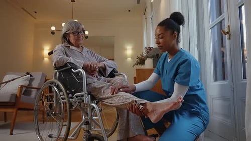 Nurse attends senior woman in wheelchair at home