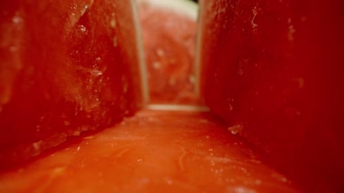Seedless watermelon halves, camera gliding along them. Macro shot, black background.