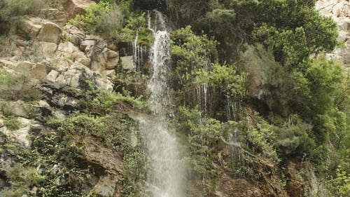 Ein Wasserstrahl fließt und spritzt von einem Felsen herab und stürzt durch die Steine