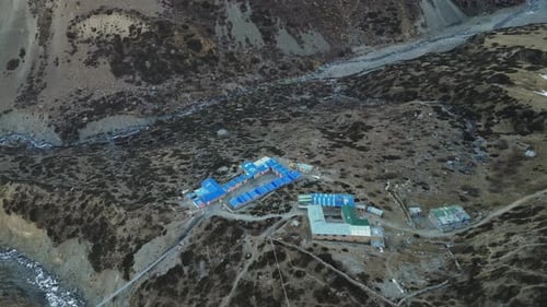 Flying around building complex in highlands of nepal in between rocky mountain scenery