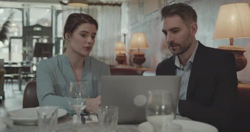Two Businesspeople having a Meeting in a Restaurant, Using Laptop Technology