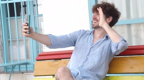 Man Waves During Cheerful Phone Chat Outdoors