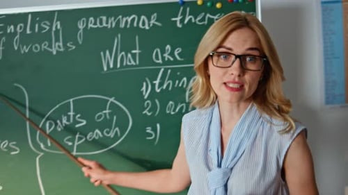 Teacher Explaining Grammar Lesson at Chalkboard