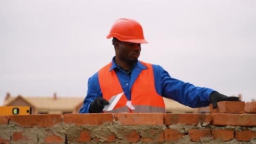 Afroamerikanischer Baumeister legt Ziegel auf der Cottage-Baustelle