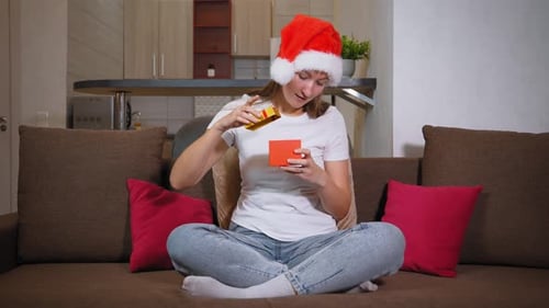 Excited Woman Opening Christmas Gift at Home