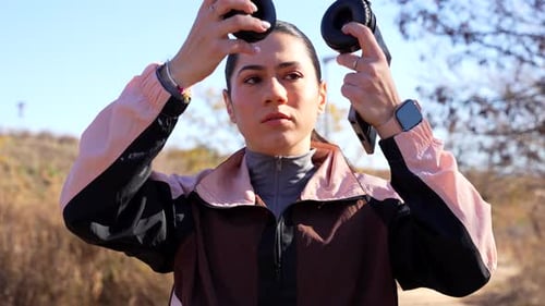 Athletic young woman putting on her headphones before a run in the park