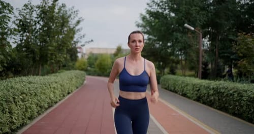 Portrait of a Happy Blue Brunette Girl in Sportswear Who Runs During Her Morning Jog in the Park