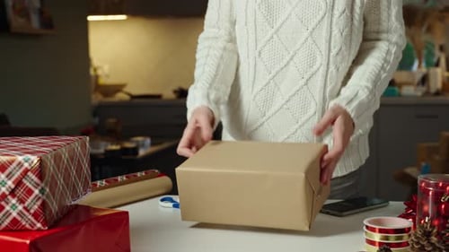 Woman Wraps Christmas Gifts at Kitchen Table
